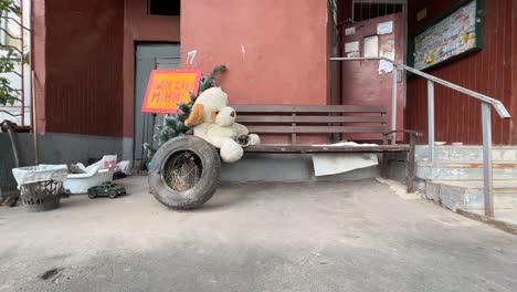 Spielzeuge-Sitzen-Auf-Der-Veranda-Eines-Verlassenen-Gebäudes-Mit-Einem-Schild-Mit-Der-Aufschrift-Gefährliche-Minen-Im-Sativka-bezirk-Von-Charkiw,-Ukraine