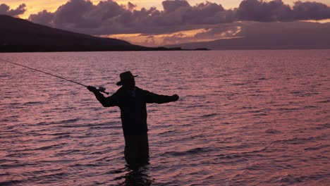Slow-Motion-Is-Employed-To-Show-A-Full-Shot-Of-Fly-Fisherman-In-Silhouette-At-Sunset-In-Molokai,-Hawaii
