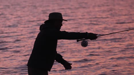 Slow-Motion-Is-Employed-To-Show-A-Medium-Shot-Of-A-Fly-Fisherman-In-Silhouette-At-Sunset-In-Molokai,-Hawaii