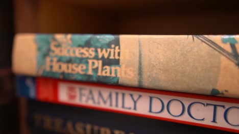 A-closeup-truck-pan-tracking-down-the-spine-of-two-household-nonfiction-books-stacked-on-a-bookshelf-about-plants-and-family-healthcare