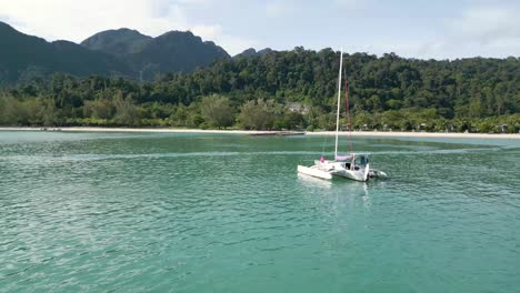 A-yacht-arriving-at-Pantai-Kok-Beach,-Langkawi,-island-with-jungle-and-mountain