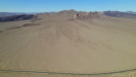 Aerial-Flying-Over-Arid-Desert-Landscape-With-Road-Running-Through