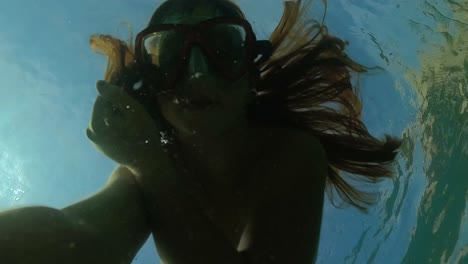 Unterwasser-Selfie-Eines-Jungen-Rothaarigen-Mädchens-Mit-Tauchmaske,-Das-Luftblasen-Macht,-Während-Es-In-Transparentem-Meerwasser-Schwimmt