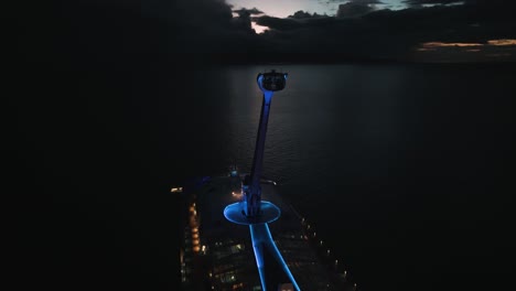 Aerial-drone-rotating-shot-over-sky-tower-observation-capsule-thing-of-a-cruise-ship-at-night-time
