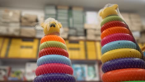 An-arc-around-the-base-of-a-kids-rainbow-coloured-hoop-stacking-toy-on-the-shelf-in-a-toy-store