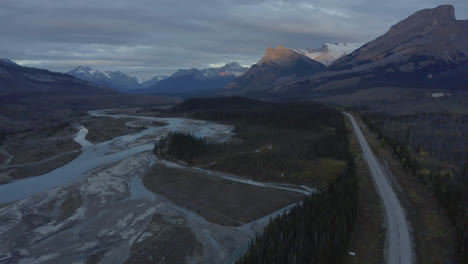 Aerial-establishing-view-of-river-valley-as-sunlight-hits-Rocky-Mountains,-Nordegg,-Alberta