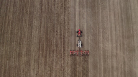 Wide-angle-bird's-eye-view-of-farmer-seeding-field,-Saskatchewan,-Canada