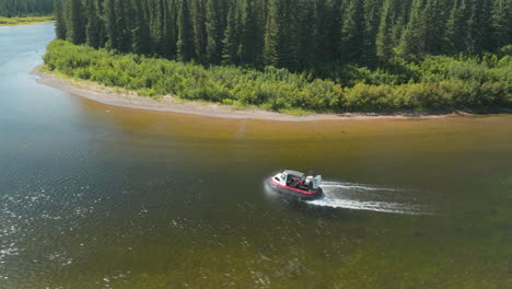 Gorgeous-drone-shot-tracking-on-an-air-boat-gliding-up-river-in-Labrador,-Canada
