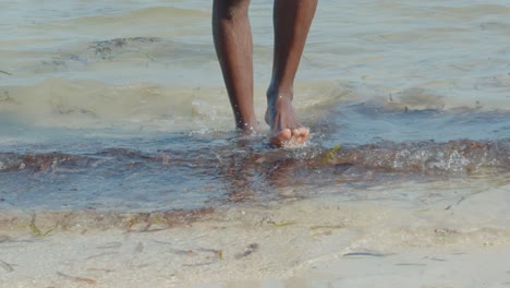Die-Nackten-Unterschenkel-Und-Füße-Eines-Schwarzen,-Der-Bei-Ebbe-Zwischen-Den-Wasserpflanzen-Im-Ozean-Spaziert