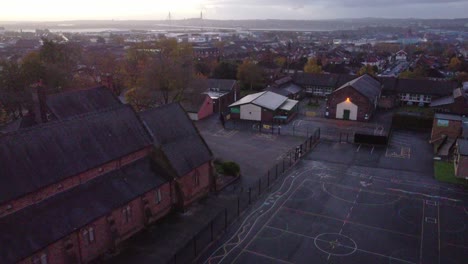 Descending-early-morning-school-playground-aerial-view-industrial-town-churchyard-at-sunrise