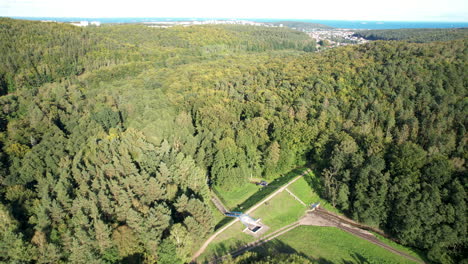 Aerial-flyover-beautiful-forest-trees-in-front-of-Gdynia-City-and-Baltic-Sea-during-sunlight