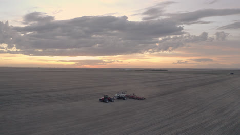 Aerial-parallax-around-lone-tractor-seeding-field-in-Saskatchewan,-Canada