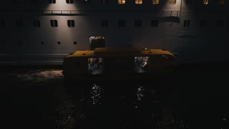 Close-up-shot-of-passengers-getting-off-from-a-cruise-ship-on-a-yellow-tender-boat-after-a-trip-at-night-time