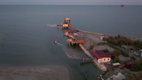 Aerial-view-of-fishing-huts-on-shores-of-estuary-at-sunset,italian-fishing-machine,-called-""trabucco"",Lido-di-Dante,-Ravenna-near-Comacchio-valley