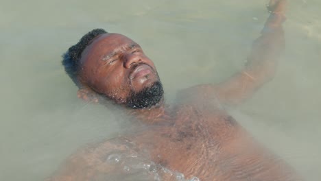 a-bare-chested-black-man-falls-backward-into-the-ocean-and-enjoys-the-water