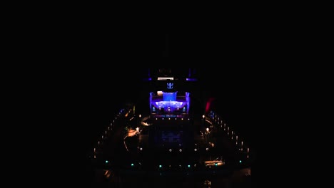 Aerial-drone-tilt-down-shot-of-stern-of-luxury-cruise-ship-at-night-time