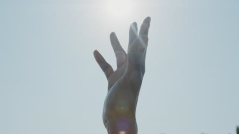 Die-Hand-Eines-Schwarzen-Mannes-In-Der-Luft-Gegen-Die-Hellen-Sonnenstrahlen