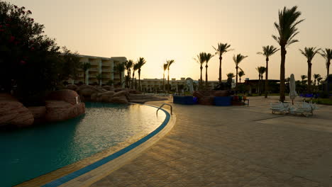 Luxus-Hotel-Resort-Swimmingpool-Im-Freien-Bei-Sonnenaufgang-In-Ägypten,-Dolly-Szene-Am-Frühen-Morgen-Am-Pool-Mit-Leerem-Gartenpoolbereich,-Tourismusurlaub-Und-Luxus