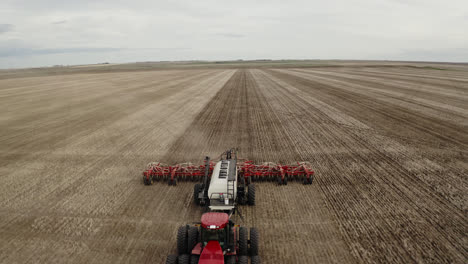 Tractor-pulls-large-seeder-through-Saskatchewan,-Canada-field
