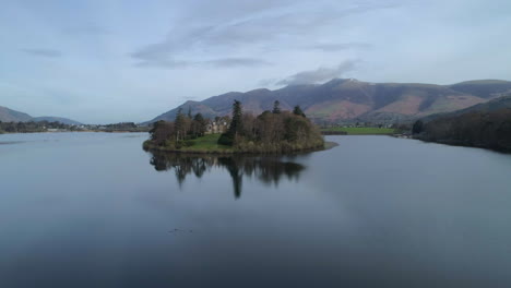 Aerial-Drone-Shot-over-Derwentwater-Lake-Keswick-with-Derwent-Island-House-and-Skiddaw-in-Shot-at-Sunrise-on-Sunny-Day-with-Clouds-Lake-District-Cumbria-United-Kingdom