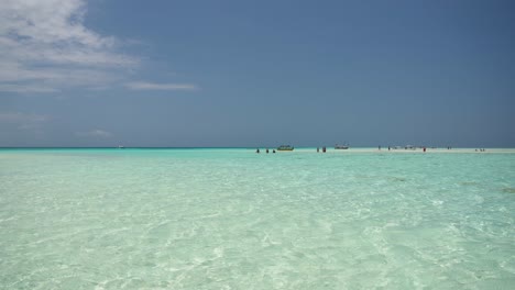 Bathers-entering-shallow-tropical-waters-of-Prison-Island-in-Zanzibar,-Tanzania-Africa,-Wide-far-shot