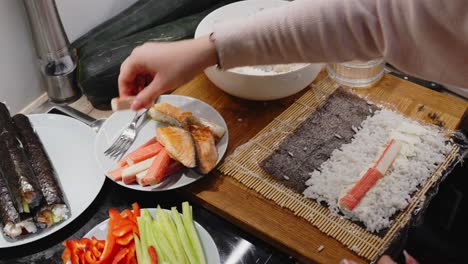 Persona-Agregando-Cangrejo-En-Rollo-De-Sushi,-Preparándose-Para-La-Cena-En-Casa