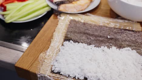 Zooming-Out-From-White-Rice-On-Wooden-Mat,-Ready-For-Sushi-Preparation