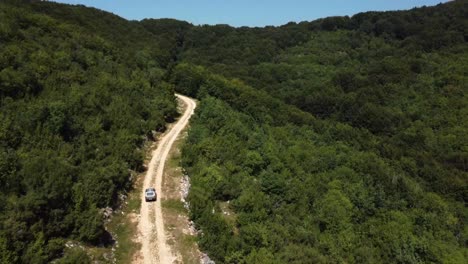 Ascending-aerial-of-4x4-car-driving-off-road-into-the-forest