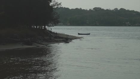 A-stationary-canoe-just-off-the-bank-of-the-Mandovi-River-surrounded-by-the-beautiful-natural-landscape-along-the-riverbank