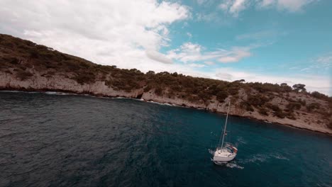 FPV-aerial-of-an-amazing-sailboat-motoring-his-way-out-of-the-bay-in-europe