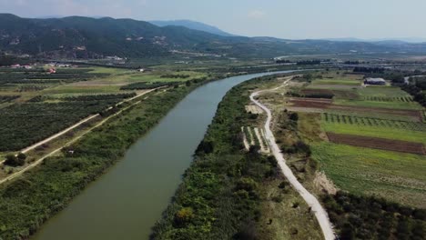 Aerial-view-over-river-running-through-the-fields-in-countryside,-Strimonas-river,-Greece