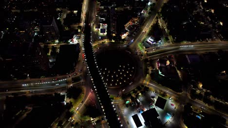 Aerial-view-at-night-of-a-large-traffic-circle-with-dozens-of-vehicles-in-congested-traffic