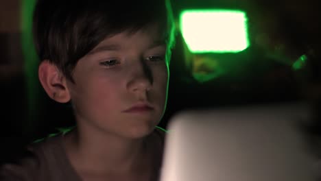 A-child-sits-in-the-dark-at-a-computer