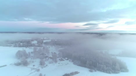 Aerial-drone-shot-flying-above-the-picturesque-countryside-covered-in-fresh-powder-snow-through-white-clouds-during-evening-time