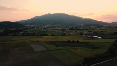 Aerial-pull-back-of-mountain-and-village-in-countryside-at-sunset,-Pangaio,-Greece