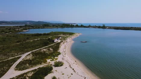 Aerial-view-over-river-estuary-and-beach-with-abandoned-building,-Strimonas-river,-Greece