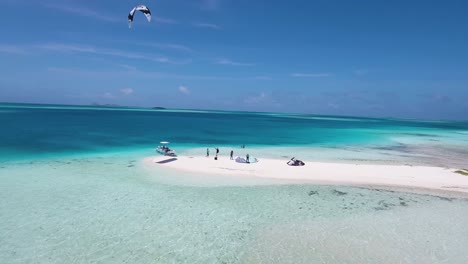 Drone-shot-kites-on-white-sand-atoll,-man-kitesurf-crystal-caribbean-sea-,-Los-Roques