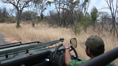 safari-vehicle-driving-through-the-dried-grasslands-in-Zimbabwe,-Africa-on-a-game-drive-with-a-guide