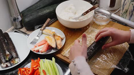 Dama-Rodando-Sushi-Verde-Sobre-Alfombra-De-Madera,-Preparación-Casera