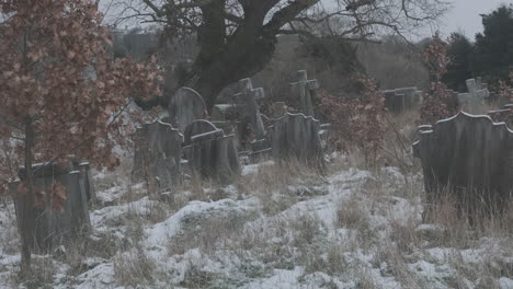 Lonely-Graveyard-Dusted-in-Snow,-with-a-Disorder-of-Neglected-and-Overgrown-Graves-and-Gnarly-trees