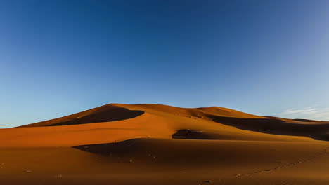 Time-lapse-shot-of-sandy-desert-dunes-in-Africa-during-sunny-sunrise-and-blue-sky