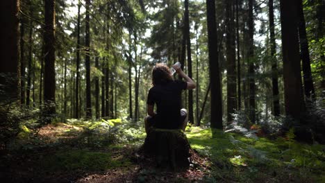 Hiker-enjoys-a-peaceful-break-in-forest-and-drinks-water
