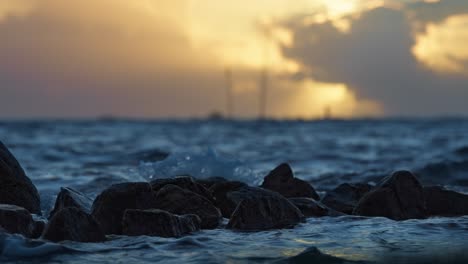 Filmisches-Meerwasser-In-Zeitlupe,-Das-Im-Wunderschönen-Sonnenuntergang-Auf-Die-Felsen-Trifft