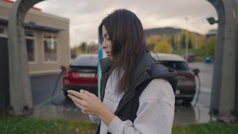 Woman-charging-EV-using-phone