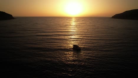 A-wide-shot-of-a-small-fishing-boat-throws-nest-while-the-sun-sets-in-beautiful-Greece-while-the-sea-is-calm