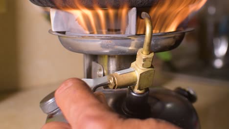 Hand-turns-on-kerosene-camp-stove,-manipulates-ignition-knob-to-get-flame,-close-up