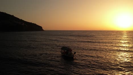 A-small-fishing-boat-throws-nest-while-the-sun-sets-in-beautiful-Greece-while-the-sea-is-calm