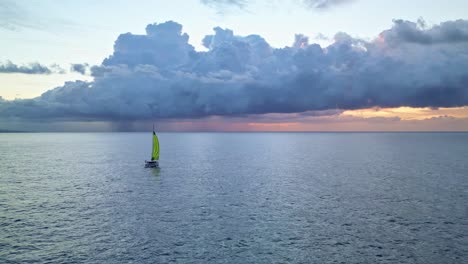 a-lone-catamaran-plying-the-ocean-with-a-storm-formation-at-sunrise