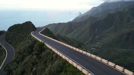 Vista-Aérea-De-Una-Carretera-Sin-Tráfico-En-Las-Montañas-Con-El-Mar-De-Fondo-En-Tenerife