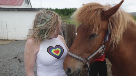 Woman-kissing-and-petting-brown-Icelandic-horse-in-Iceland-on-ranch